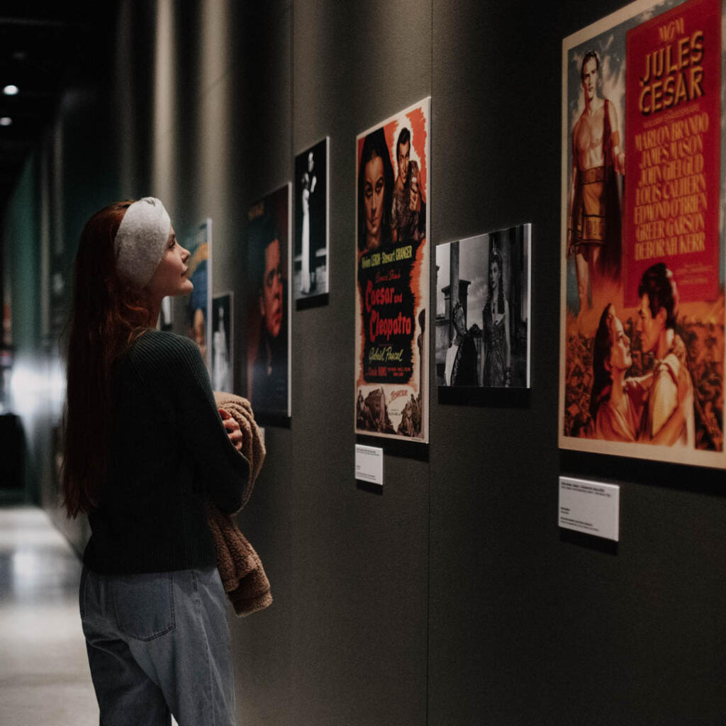 Henkilö katselee elokuvajulisteita museon näyttelyssä.
